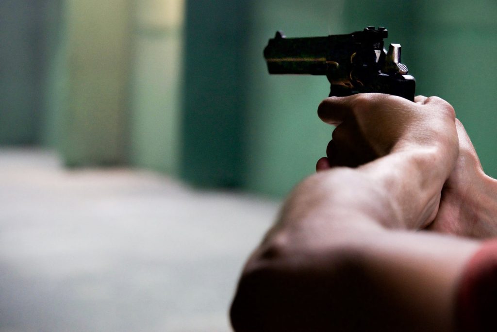 homem segurando arma apontando para reféns