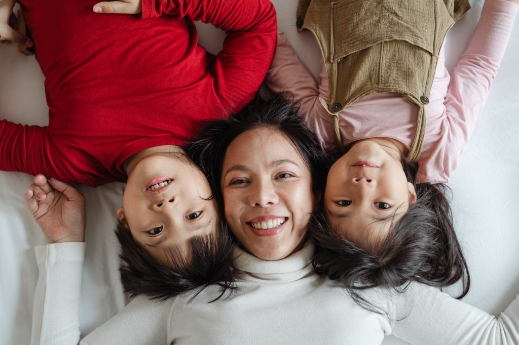 mãe e duas filhas meninas crianças deitadas na cama causas de autismo